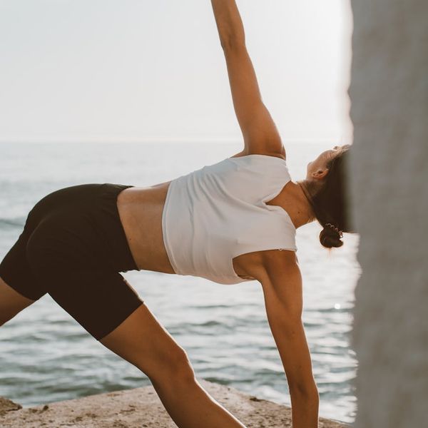 Person stretching outdoors at sunrise, feeling energized.